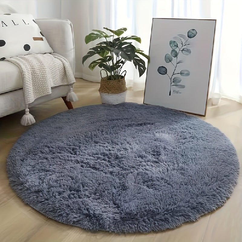 Round blue rug in a living room with a sofa, plant, and artwork.