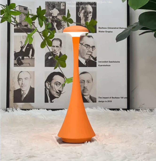 Orange lamp on a white surface with a framed poster in the background