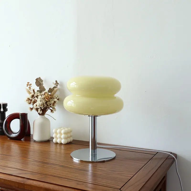 Yellow stool on a wooden surface with decorative items against a white wall