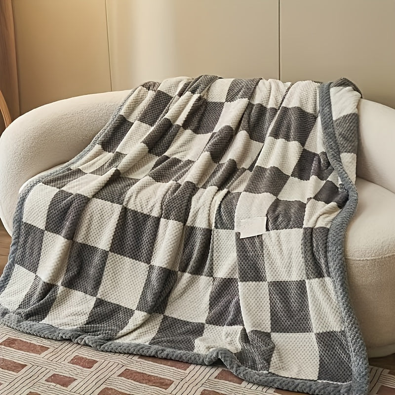 Checkered blanket draped over a beige armchair on a patterned floor.