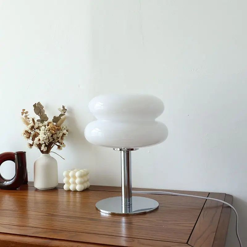 White table lamp on a wooden surface with decorative items in the background