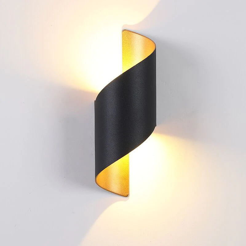 Modern wall light fixture with black and gold design on a gray background