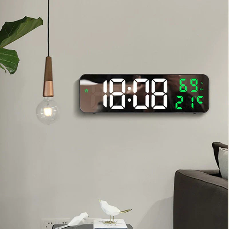 Digital wall clock with large LED display on a light gray wall.