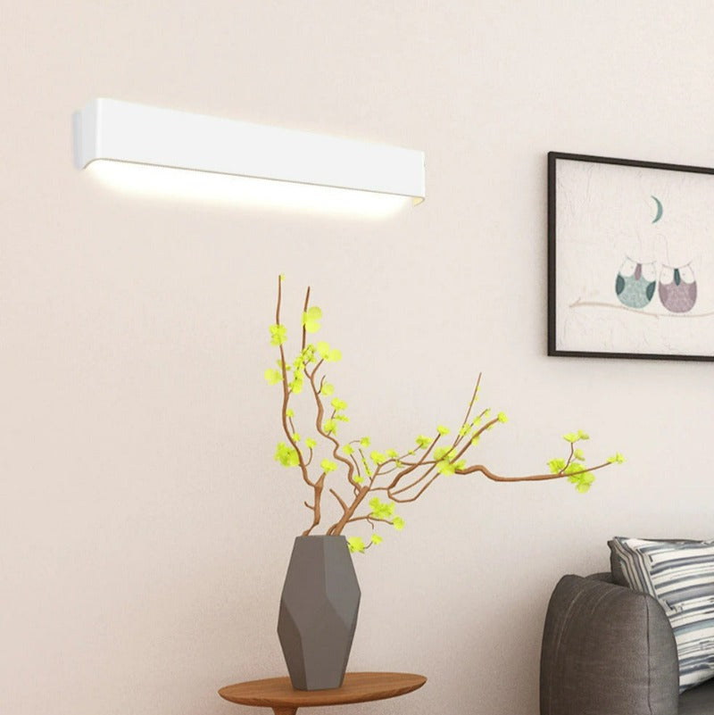 Modern living room with a wall-mounted light fixture, side table, and sofa.