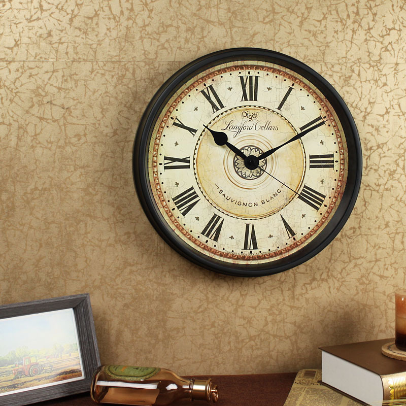 Decorative wall clock with Roman numerals on a textured beige wall.