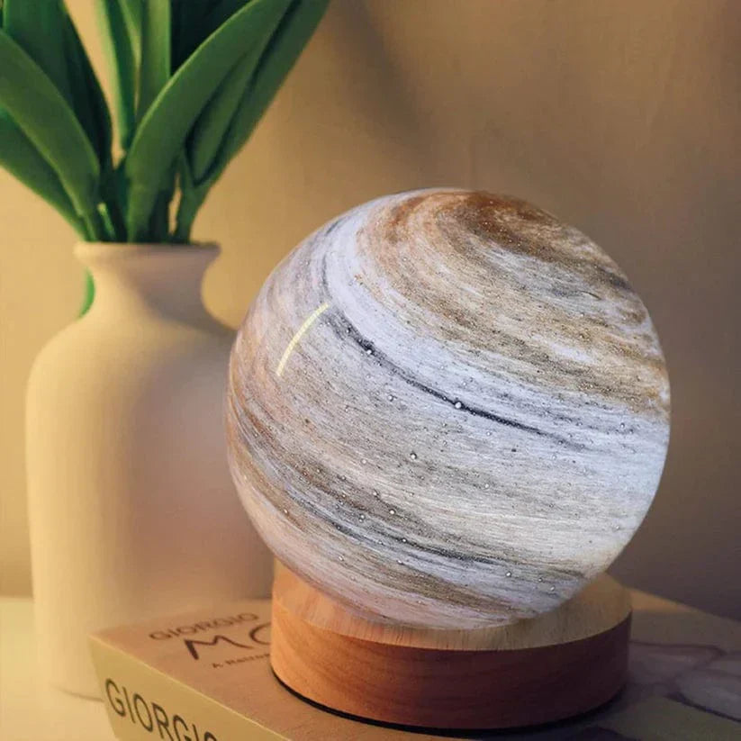 Marble-patterned lamp on a wooden base with a plant in the background