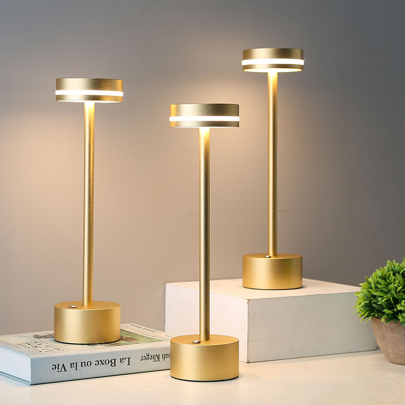 Three gold table lamps on a neutral background with a plant and book.
