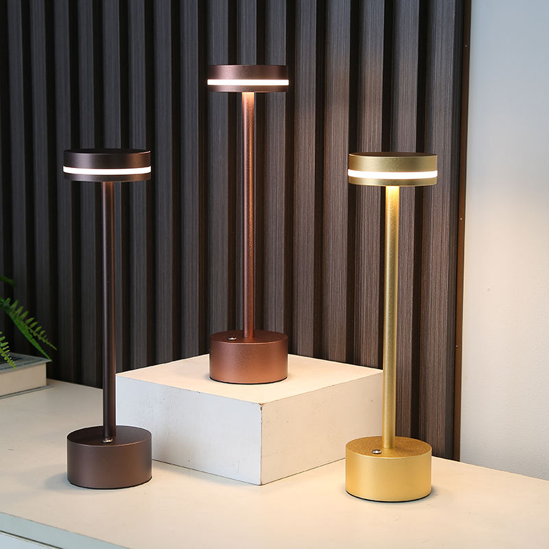Three modern table lamps in bronze, silver, and gold on a neutral background