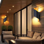 Modern outdoor living space with wall lights, sofa, and fire pit.