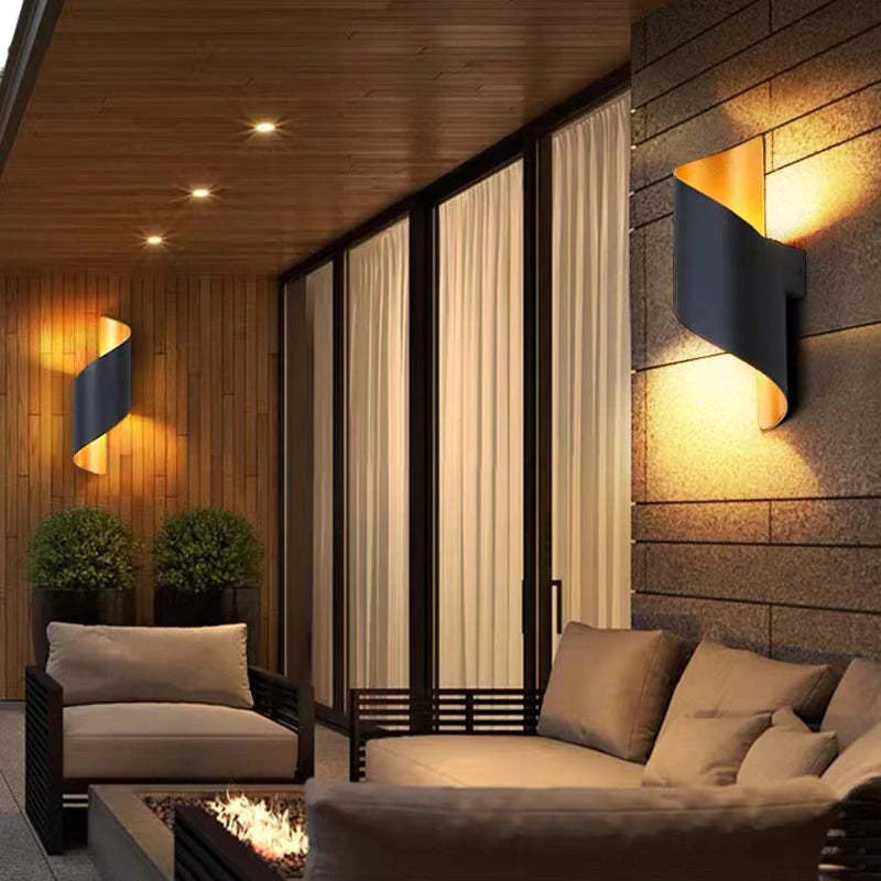 Modern outdoor living space with wall lights, sofa, and fire pit.