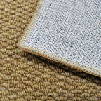 Close-up of a textured beige carpet corner with a white underlay.