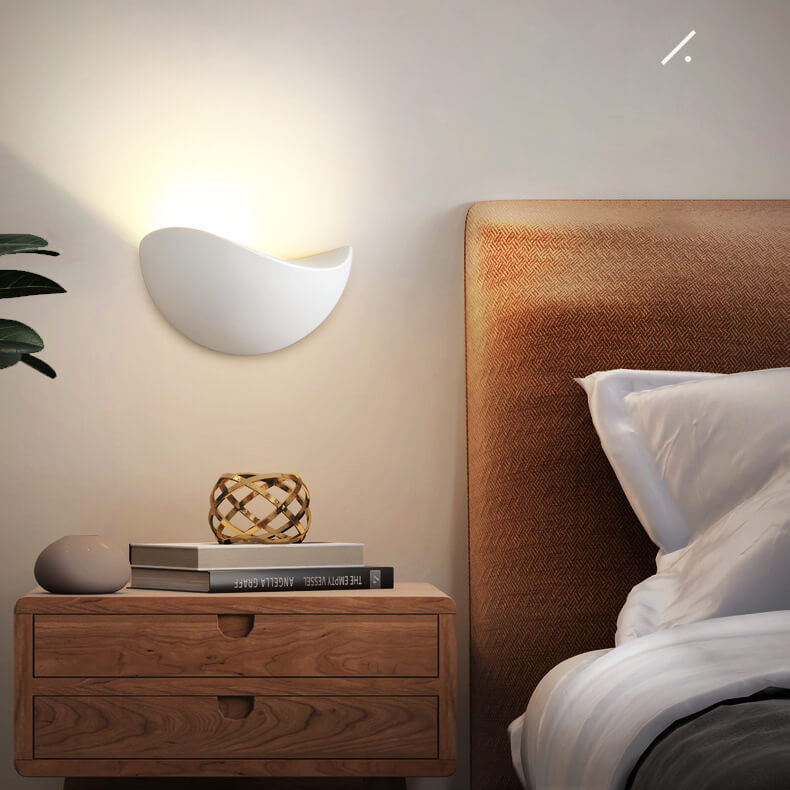 Bedroom scene with wooden nightstand, decorative items, and bed with pillows.