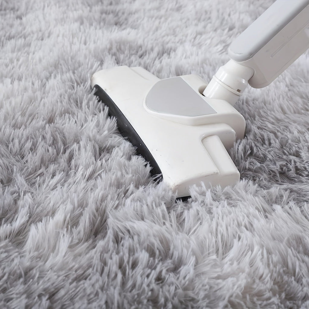 White vacuum cleaner cleaning a gray carpet