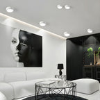 Modern living room with a black and white portrait on the wall, white sofa, and glass coffee table.