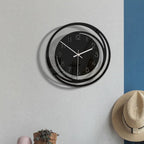 Wall clock on a wall with a hat and plant below