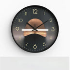 Round wall clock with black frame and gold numbers on a white background