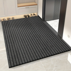 Textured black doormat on a tiled floor with shoes in the background