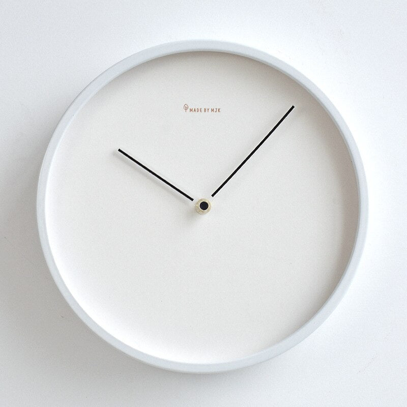 White wall clock with black hands on a light gray background