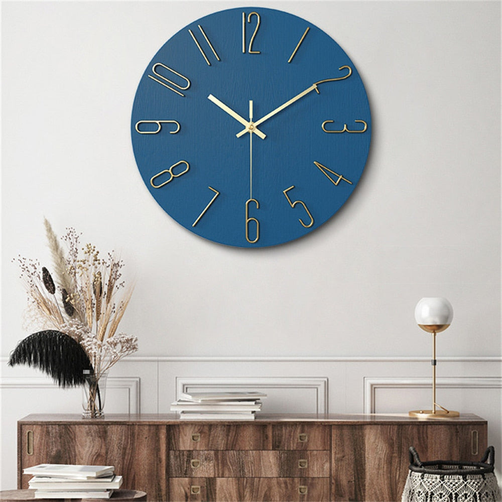 Blue wall clock with gold numbers on a white wall above a wooden console table.