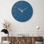 Blue wall clock with gold numbers on a white wall above a wooden console table.
