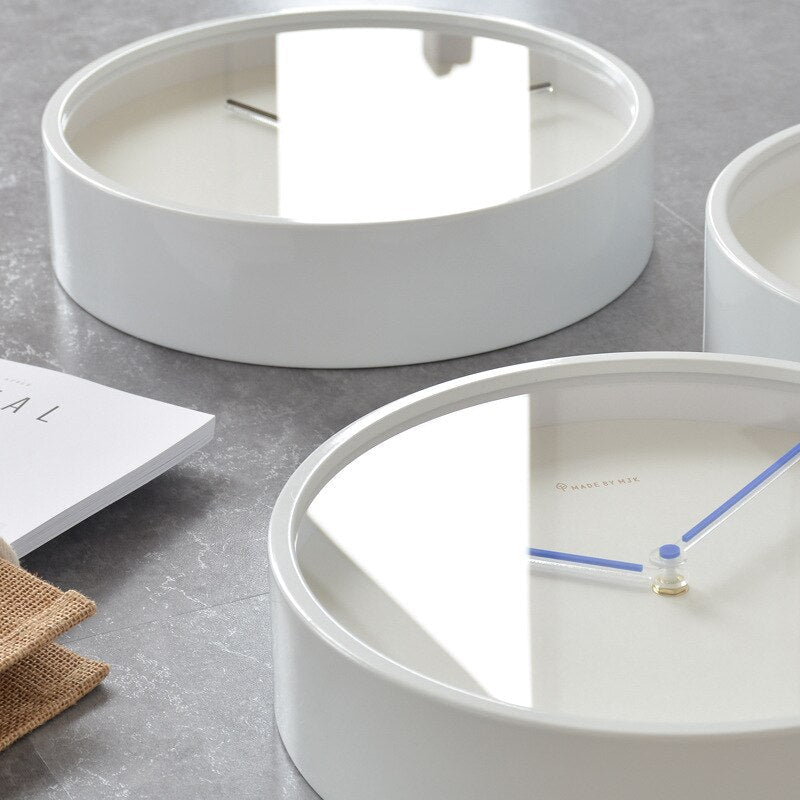 White circular clock on a gray surface with a minimalistic design.