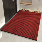 Red striped doormat in front of a door with shoes on a shelf in the background.