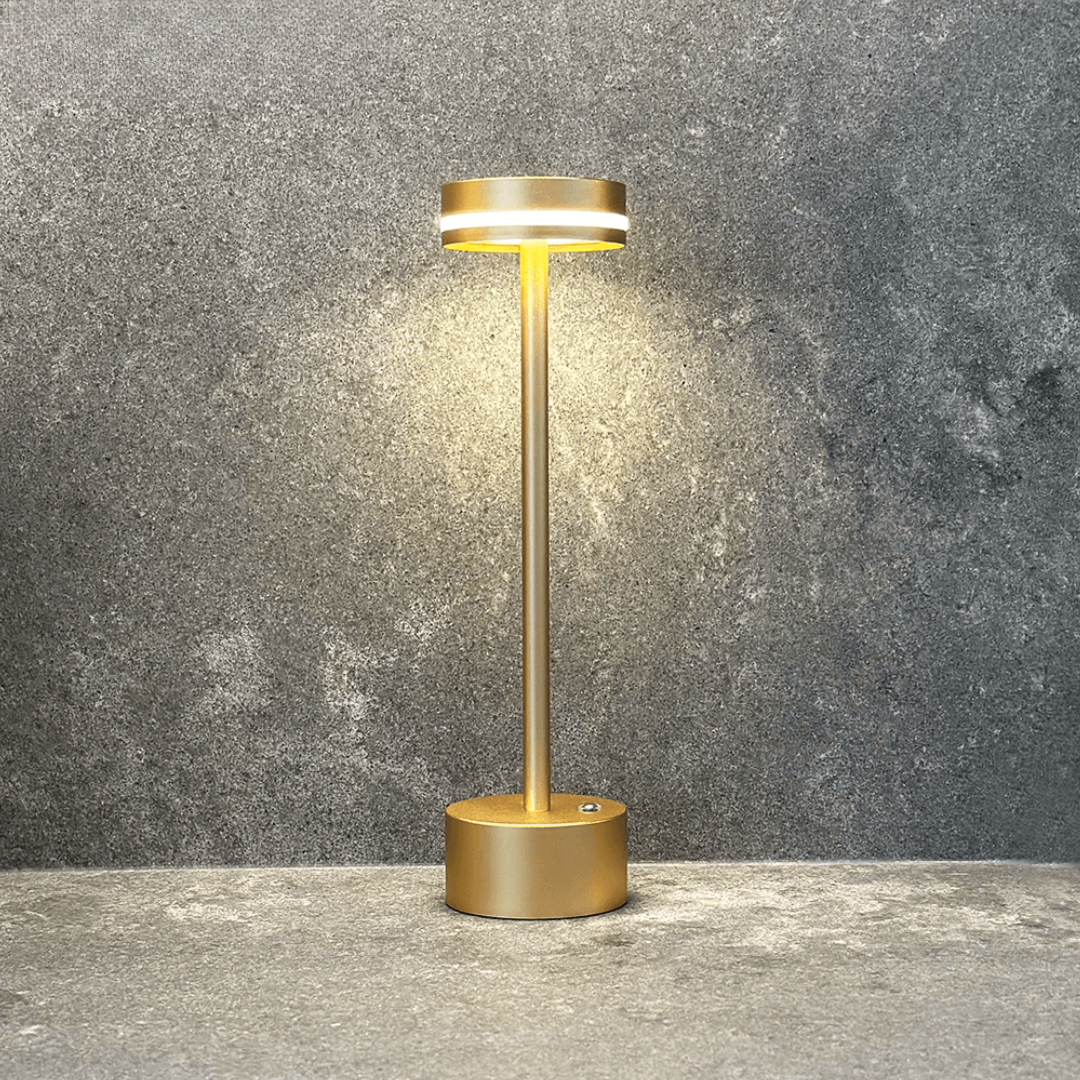 Gold outdoor lamp on a gray concrete surface with a gray concrete wall background