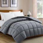 Gray comforter on a bed in a bedroom with a lamp and window.