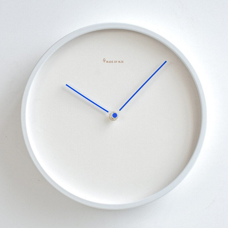 White wall clock with blue hands on a light gray background