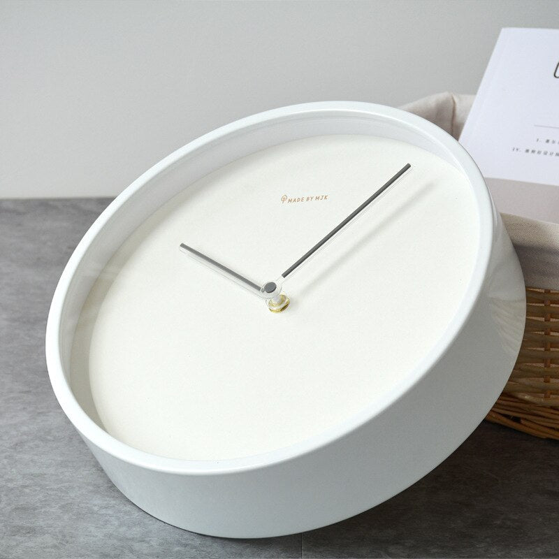 White wall clock with minimalist design on a gray surface
