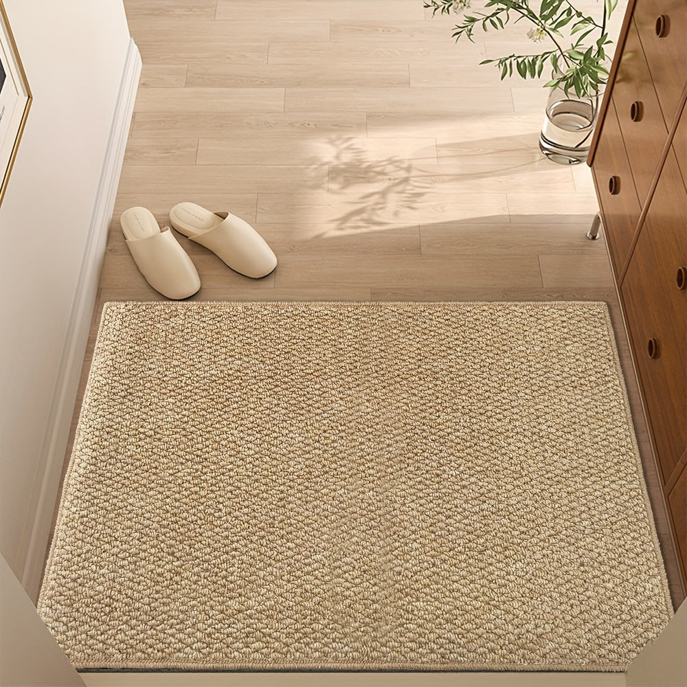 Beige doormat on a wooden floor with white slippers and a plant in the background
