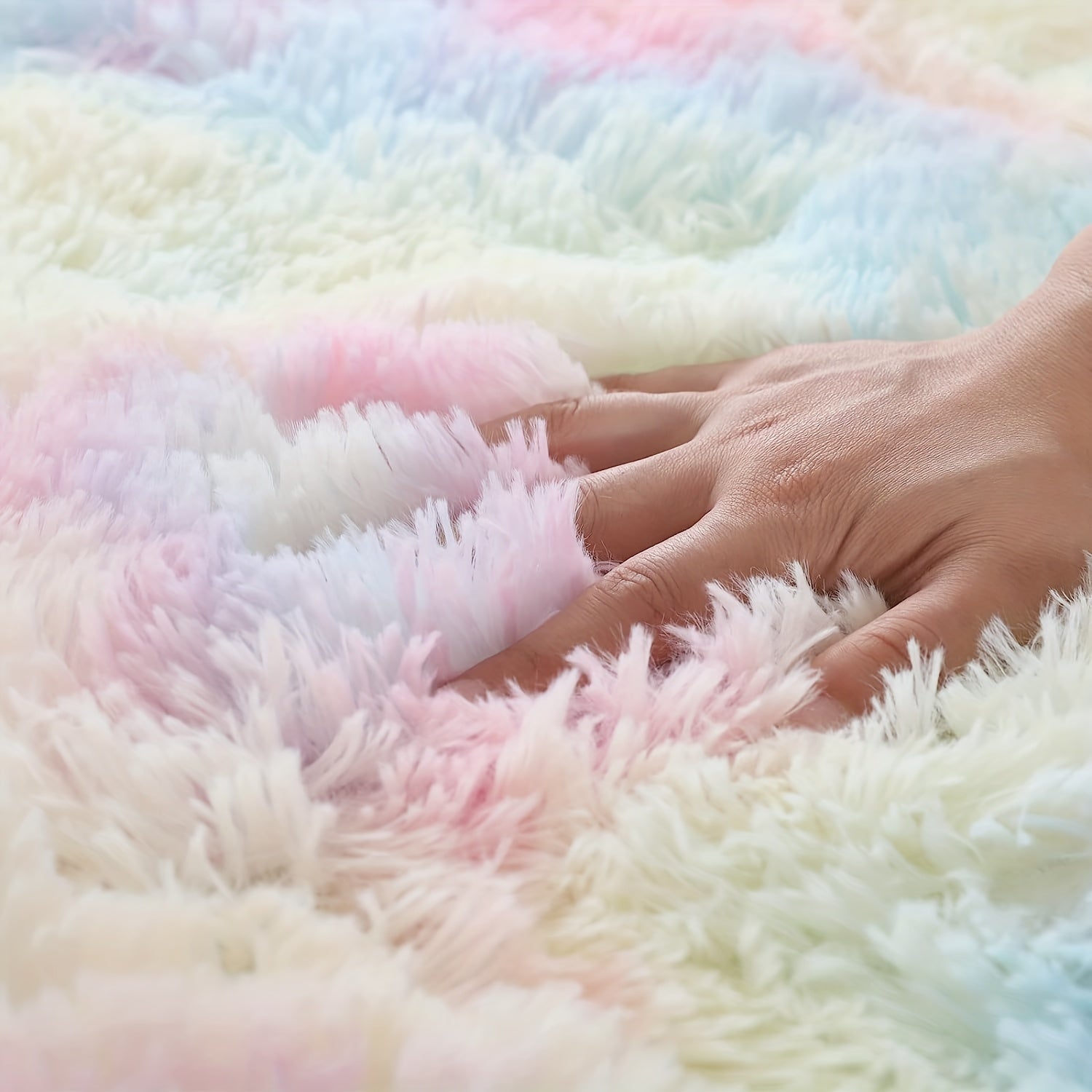 Close-up of a hand touching a fluffy, multicolored blanket.