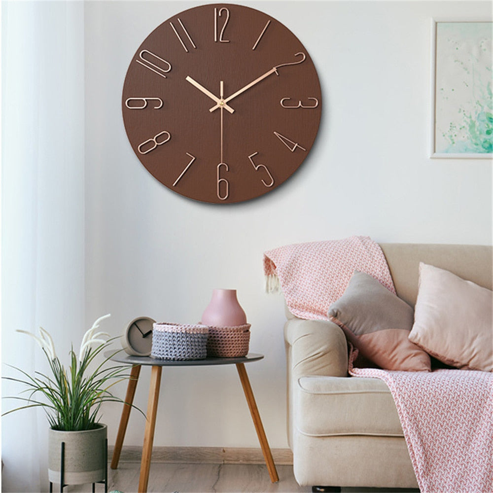 Brown wall clock on a white wall above a beige sofa with pink and gray cushions.