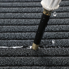 Close-up of a black garden hose with brass fitting on a textured surface.