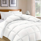 White comforter on a bed in a bedroom setting with a lamp and window.