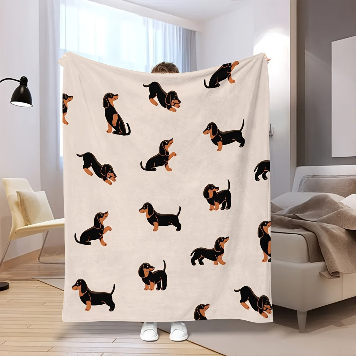 Person holding a blanket with dachshund pattern in a room.