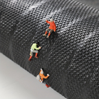 Three small figurines climbing a textured black surface