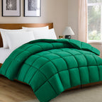 Green comforter on a bed in a bedroom with a lamp and window.