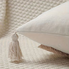 Beige pillow with tassel on a textured surface