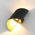 Modern wall-mounted light fixture with black and gold design on a white wall.