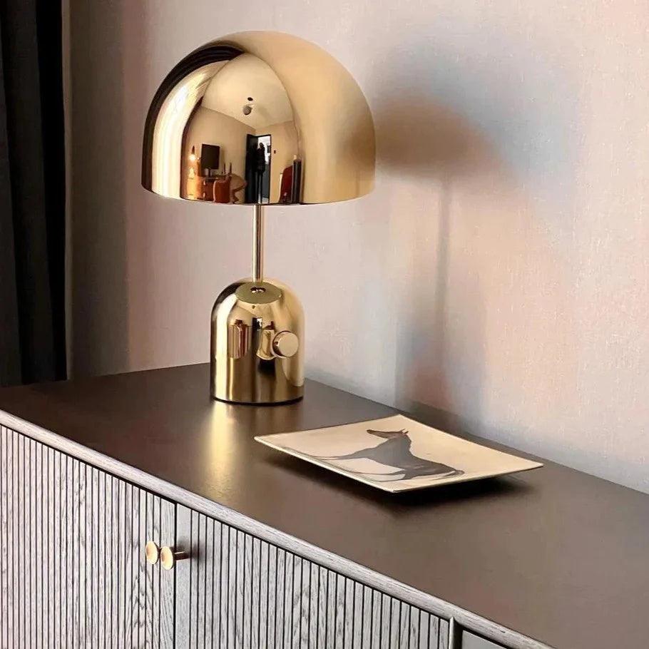 Gold table lamp on a wooden surface with a blurred background