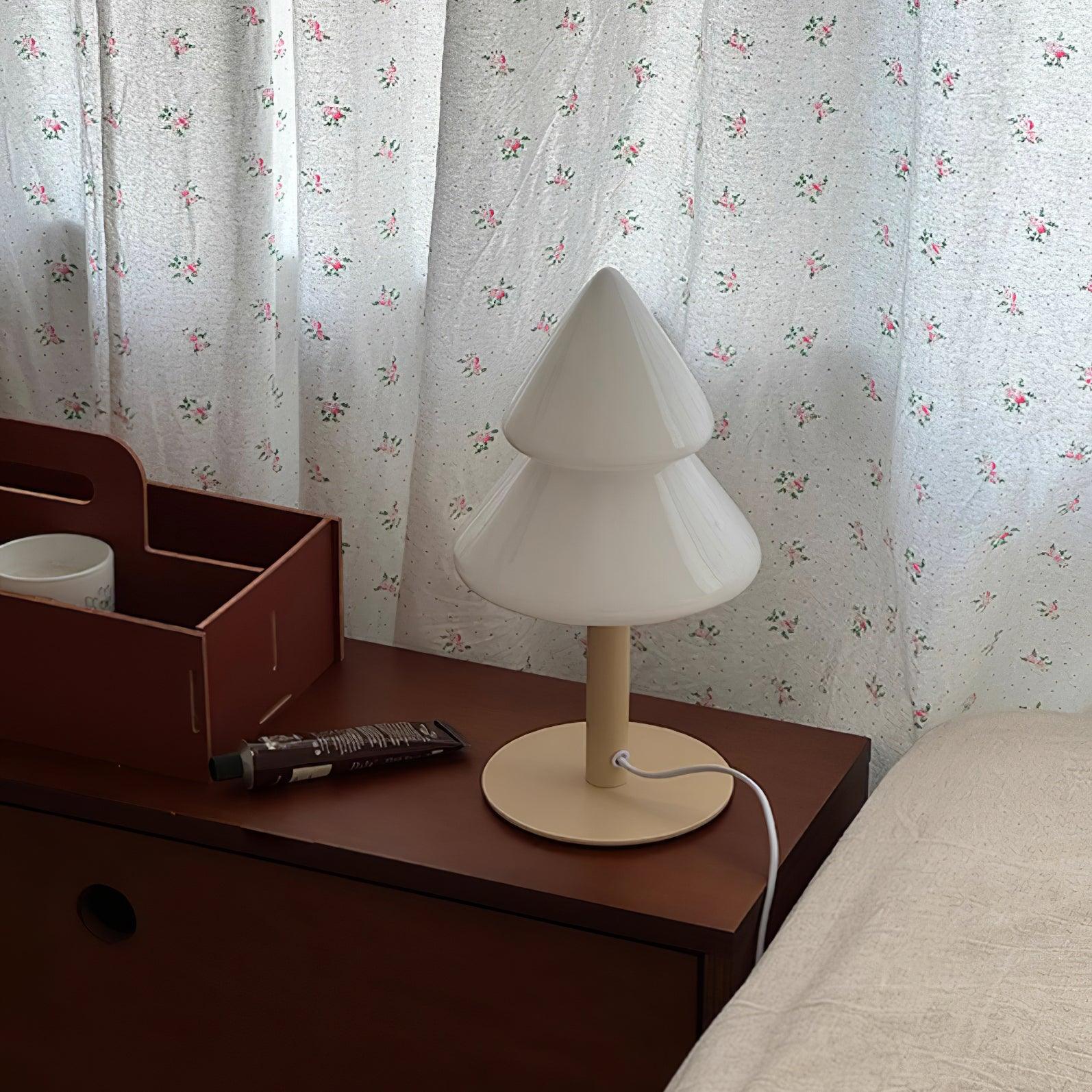 White lamp on a wooden nightstand with floral curtains in the background