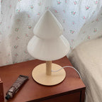 White table lamp on a wooden surface with floral wallpaper in the background