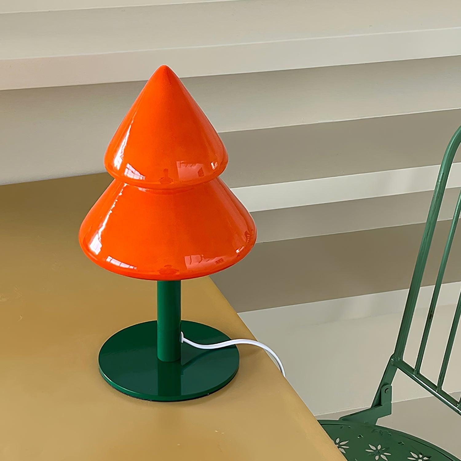 Orange and green lamp on a table with a striped wall in the background