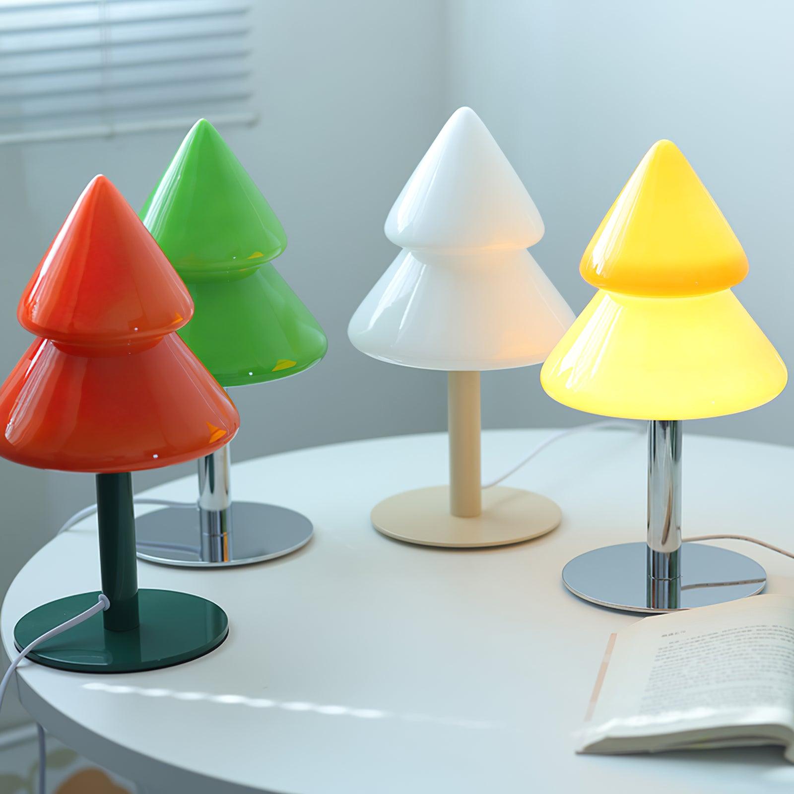 Four colorful tree-shaped lamps on a round table with a neutral background