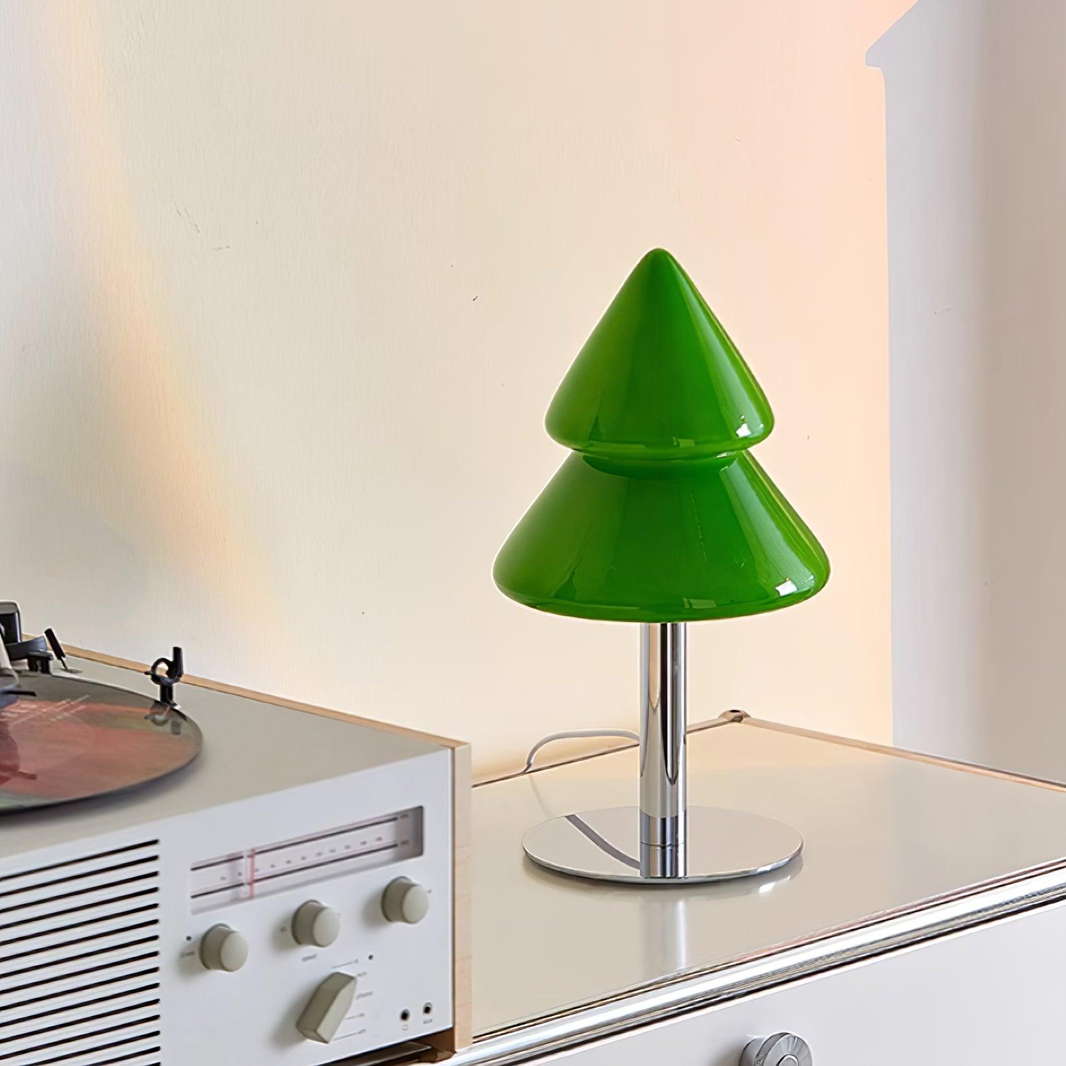 Green cone-shaped table lamp on a vintage record player with a warm glow.