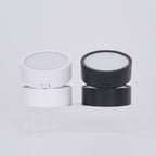 Two cylindrical containers, one white and one black, on a light gray background.