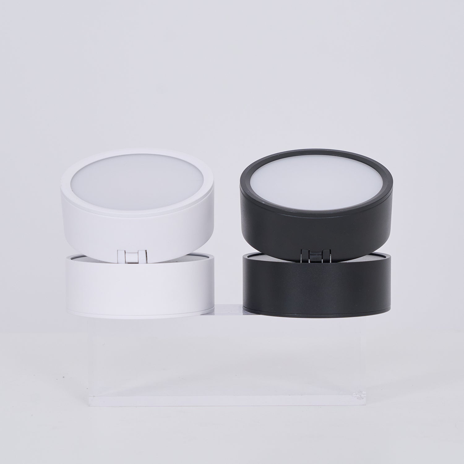 Two cylindrical containers, one white and one black, on a light gray background.