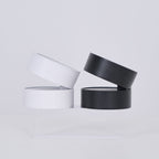 Two black cylindrical containers with clear lids on a light gray background