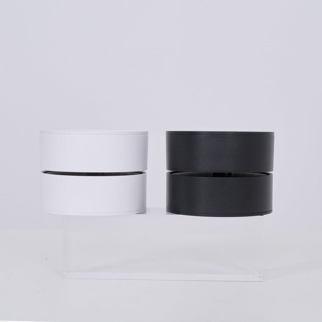 Two cylindrical lamp, one white and one black, on a light gray background.